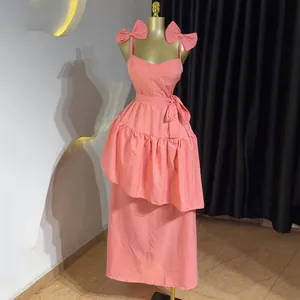 Vue détaillée d'une robe midi rose avec bretelles à nœuds et volants asymétriques.