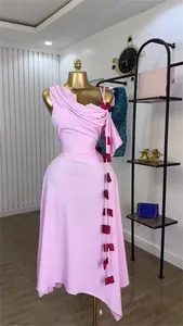 Detail view of a pink one-shoulder midi dress with decorative red bow accents.