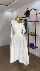 Close-up detail of an elegant white one-shoulder midi dress with decorative satin shoulder bows