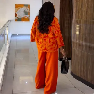 Back view of vibrant orange printed shirt and wide-leg trousers set in a stylish hallway