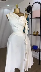 Elegant white one-shoulder midi dress with decorative bows and draped details