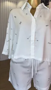 Detailopname van witte set met overhemd en korte broek met strass-steentjes