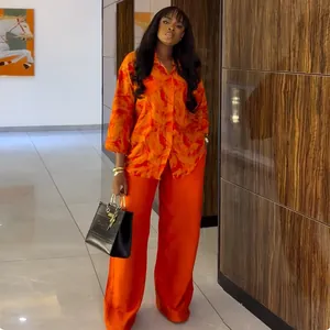 Chic two-piece set featuring orange abstract print shirt and vibrant wide-leg trousers