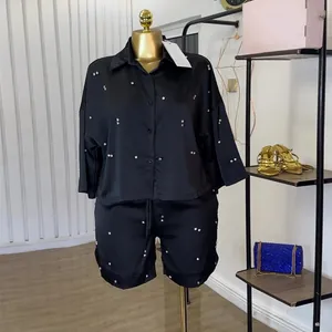Gedetailleerd overzicht van een elegante zwarte satijnen set met stras en wijde shorts