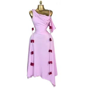 Elegant pink one-shoulder midi dress with decorative bow accents and asymmetrical hem
