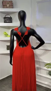 Détail arrière d'une robe longue plissée rouge avec des bretelles à fleurs 3D croisées