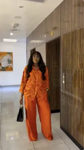 Full view of women's orange printed shirt and wide-leg trousers two-piece set on model
