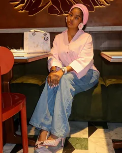 Detailansicht eines lockeren rosa Revershemdes und blauer Weitbein-Jeans im Café.
