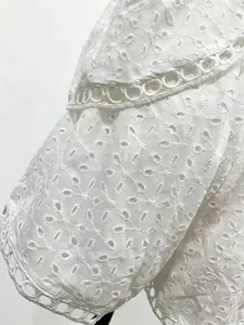 Close-up detail showing the intricate white eyelet embroidery on a summer two-piece outfit