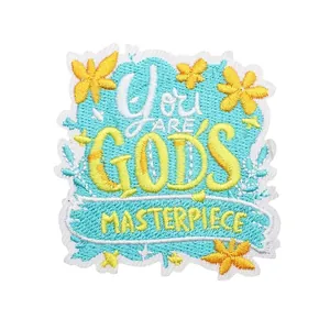 Parche bordado inspirador 'You Are God's Masterpiece' con motivos florales amarillos.