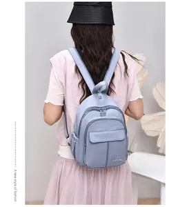 Rear view of a stylish light blue waterproof nylon mini backpack worn by a model