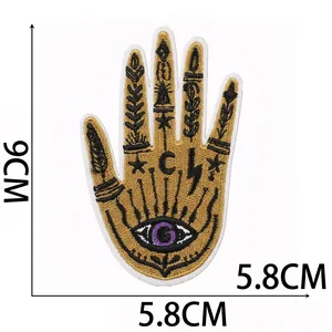 Detail of mystical gold and black Hamsa hand embroidery patch with evil eye motif