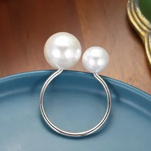 Elegant silver napkin ring with two white pearls on a blue ceramic plate for table decor