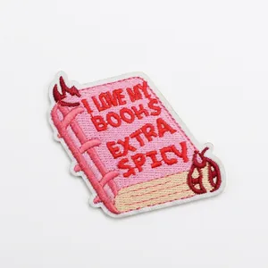Detailed view of pink 'Extra Spicy' book embroidered patch with 6cm size markings.