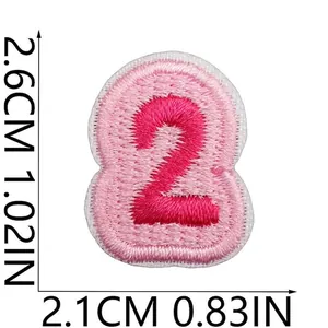 Detailansicht des rosa gestickten Aufnähers Nummer 2 mit Größenangaben 2,6 cm x 2,1 cm.