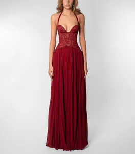 Elegant red halter maxi dress with lace bodice and pleated floor-length skirt detail.