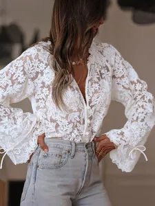 Close-up detail of white floral hollow-out lace shirt with flared sleeves and ties.