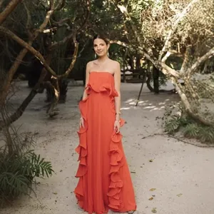 Robe maxi corail élégante sans bretelles avec plis et volants dans un jardin