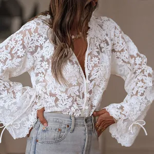 Detail view of a white hollow-out floral lace blouse with flared sleeves and ties.