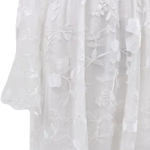 Nahaufnahme einer zarten weißen Blumenstickerei auf transparentem Hochzeitskleid-Spitzenstoff.
