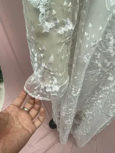 Detailaufnahme von eleganter weißer floraler Spitzenstickerei an langen Ärmeln der Robe