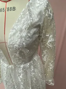 Detailaufnahme eines weißen Hochzeitskleides aus floraler Spitze mit V-Ausschnitt