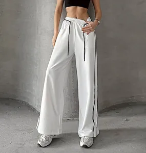 Vue détaillée du pantalon de jogging blanc à jambes larges avec bandes latérales noires.