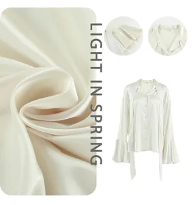 Elegant champagne satin blouse detail featuring pussy-bow neck and ruffle sleeves texture