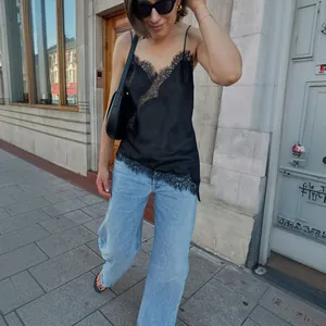 Stilvolles schwarzes Satintop mit asymmetrischem Spitzenbesatz für die Sommermode.