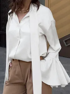Close-up of white satin blouse featuring elegant tie-neck and ruffled bell sleeves