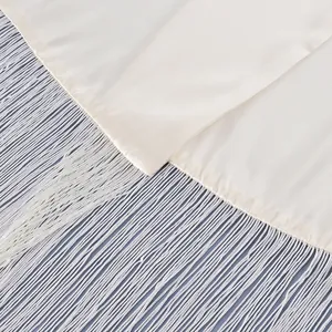 Macro view showing the elegant cream satin texture and long fringe tassels of the waist sash