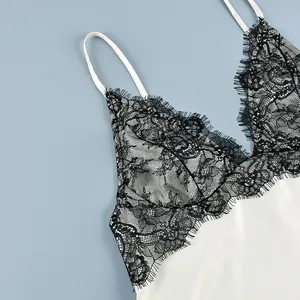 Detailed shot of delicate black eyelash lace on a white satin camisole tank top