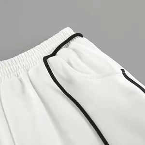 Détail de la taille élastique et du liseré noir contrasté sur un pantalon de jogging blanc.