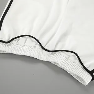 Vue détaillée de la taille élastique et des bandes latérales noires du pantalon blanc.