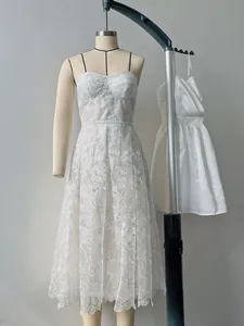 Detailed view of an elegant white lace sleeveless dress on a mannequin for shop display.