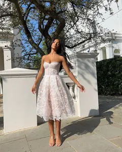 Elegant white lace strapless midi dress for summer worn in an outdoor street setting.