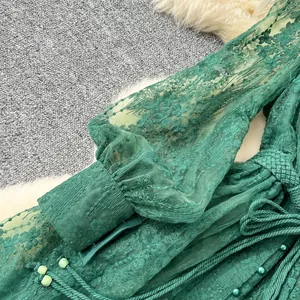 Gros plan d'une robe en dentelle vert émeraude avec des broderies florales complexes.