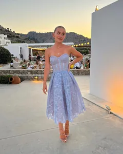 Elegant light blue lace strapless dress shown in an outdoor sunset party setting