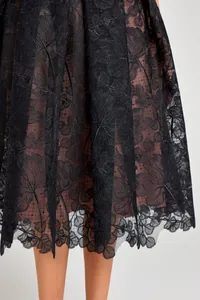Close-up of intricate black floral lace embroidery and scalloped hemline.