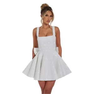 Close-up of elegant white sequin party dress featuring a large bow and square neckline.