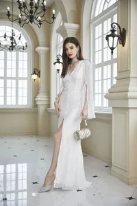 Elegante vestido de noche en encaje blanco con escote en V y mangas abiertas en pasillo