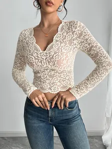 Detail shot showing intricate floral lace texture on white V-neck long sleeve top.
