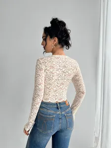 Detail view of the intricate floral lace pattern and slim fit of this white long-sleeve top