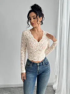 Visual detail of white floral lace V-neck long sleeve top with intricate pattern texture.