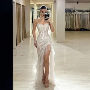 Detailed view of white strapless lace evening gown with high slit and ruffles.