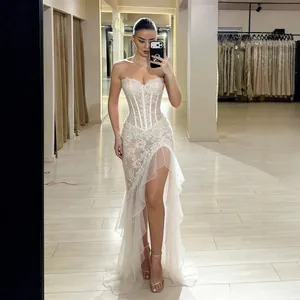 Detailed view of elegant white lace corset evening dress with high slit and ruffles