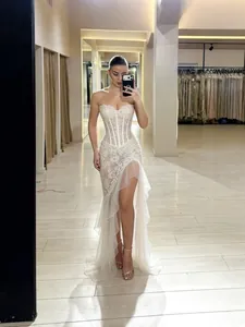 Elegant white strapless corset evening dress with lace details and ruffled high slit.