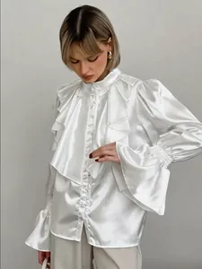 Detail view of elegant white satin blouse with ruffles, stand collar and pearl buttons