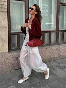 Close-up of white semi-transparent loose drawstring joggers in a stylish street setting.