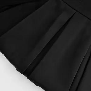 Macro view showing the sharp pleated fabric details of a minimalist black A-line dress